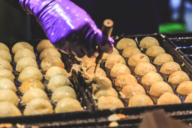 Photo of Cooking takoyaki most popular delicious snack of japan. Asian street food night market. Regional Food