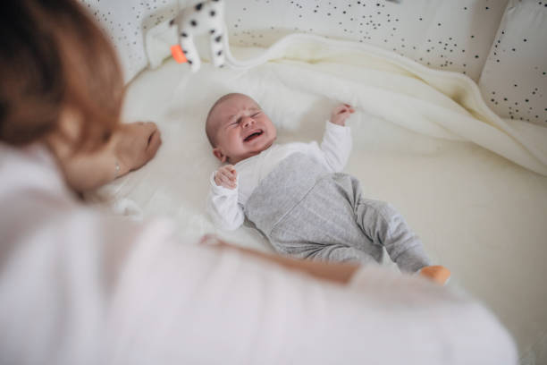 istock Baby boy lying in crib and crying 1199443486