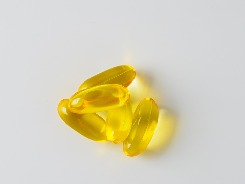 Omega 3 fish oil capsules isolated on white background. Golden color capsules - vitamin E, D or multivitamin.