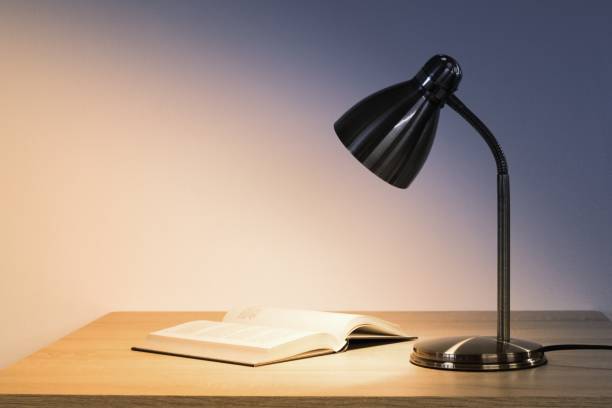 istock Lamp and book on the desk top, space for text 1199446644