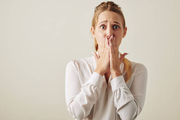 Caucasian Woman Shocked With Something Horizontal waist up studio portrait shot of Caucasian woman feeling shock looking at camera covering her mouth bad news stock pictures, royalty-free photos & images