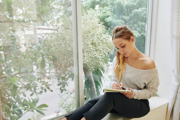 istock Young Woman On Window Sill 1199448236