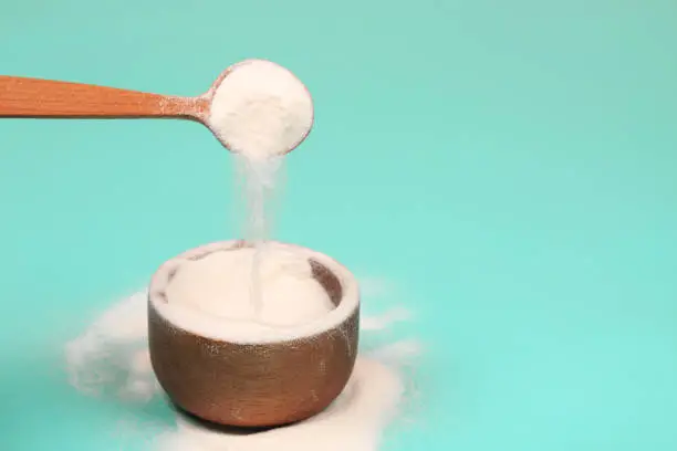 Collagen or protein in powder on teal background.