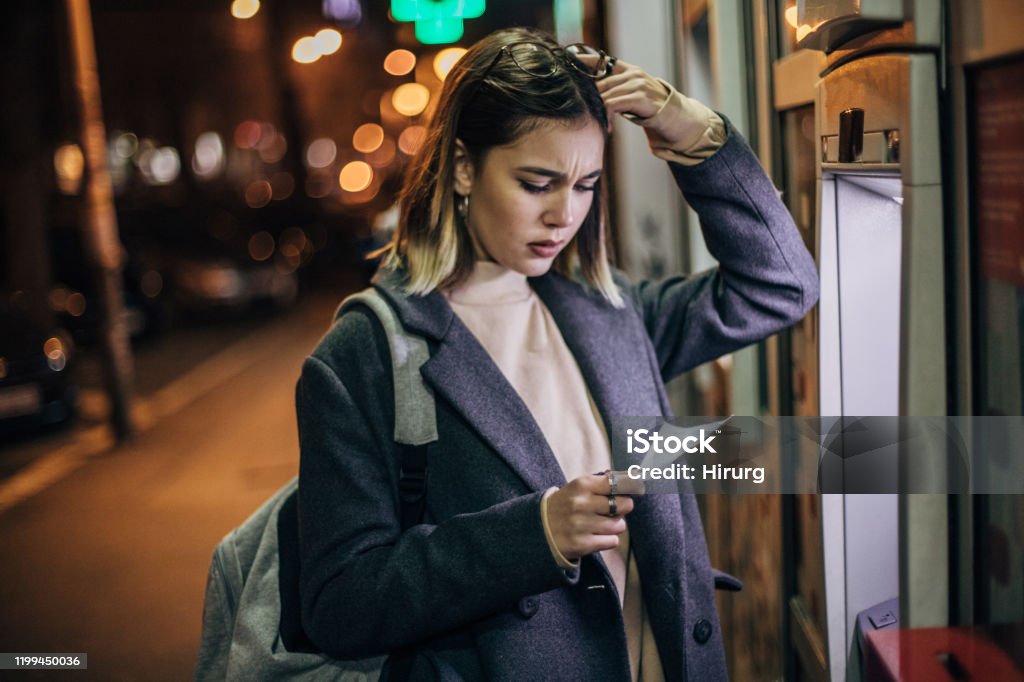 Young woman is upset in front ATM machine Worried woman with the hand on her forehead had problems with ATM machine ATM Stock Photo