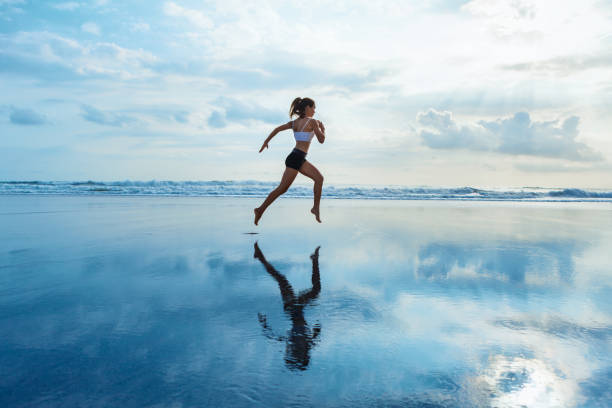 ragazza sportiva che corre in spiaggia lungo il surf sul mare - weight scale dieting weight loss foto e immagini stock