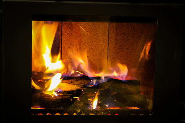 istock Burning wooden logs in a small closed fireplace 1199450792