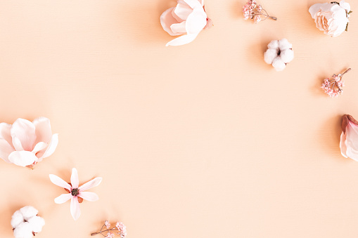 Flowers composition. Frame made of pink flowers on pastel beige background. Flat lay, top view, copy space