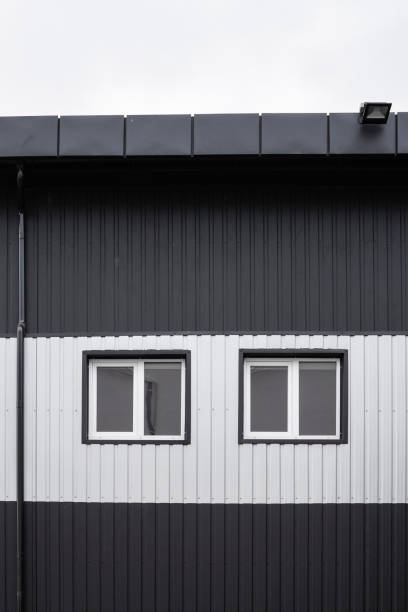 istock Black and white Corrugated metal sheet texture surface on a building wall with windows. Galvanize steel background. 1199450920