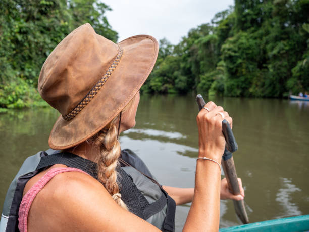 Tourist woman on canoe exploring Tortuguero Costa Rica rainforest Tortuguero Costa Rica rainforest, young woman roaring on green canoe exploring the Tortuguero canal national park, wildlife and nature reserve. tortuguero national park photos stock pictures, royalty-free photos & images