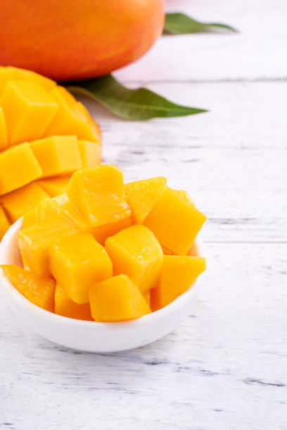 istock Fresh mango,beautiful chopped fruit with green leaves on bright wooden table background. Tropical fruit design concept. 1199454425
