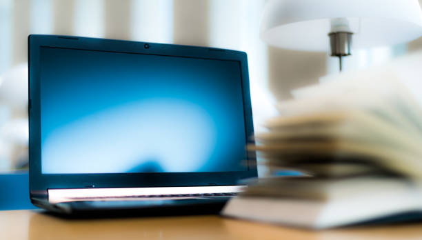istock Laptop computer and a book on the desk in public library 1199457502