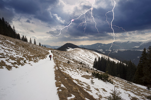 Self portrait: Traveling of a lone tourist in the snowy Carpathians among wild forests and fields, during a strong storm with a winter thunderstorm against the backdrop of mountains