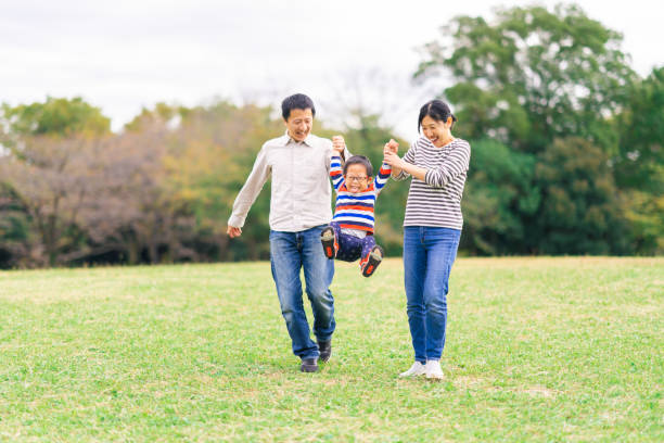 公共公園で自分の時間を楽しむ家族 - three person family ストックフォトと画像