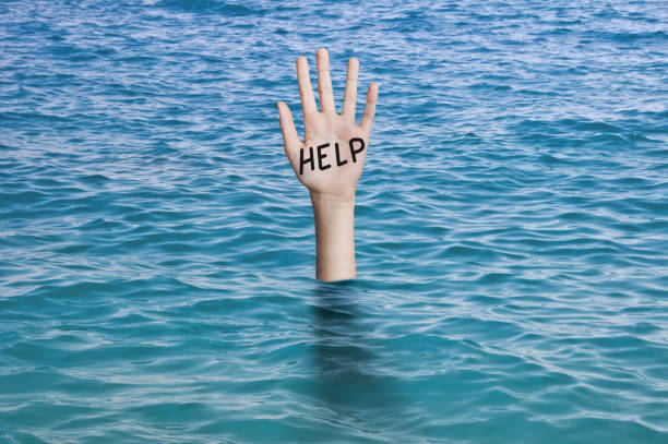 palabra ayuda escrita en la palma de una mano que se hunde en el agua del océano. ahogar a la persona concepto de emergencia, fracaso y ayuda - ahogar fotografías e imágenes de stock