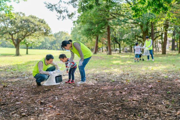 ボランティアの仕事として公共公園を掃除する家族 - 捨てる ストックフォトと画像