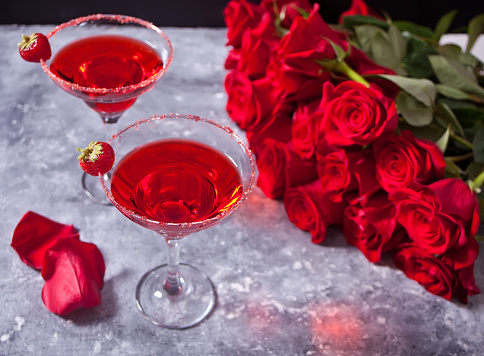 Red fresh exotic alcoholic cocktail in clear glass and red roses for romantic dinner