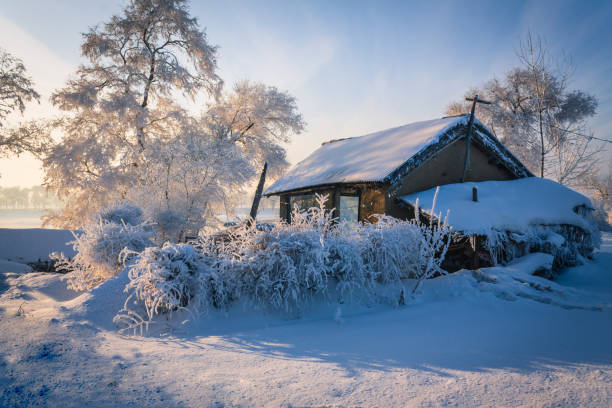 Abandoned old building on the background of temple during hard frost and fog. Backlit and sun flare.