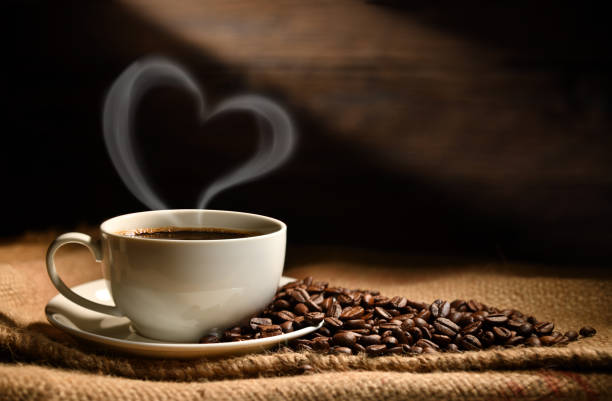古い木製の背景にバーラップ袋にハートの形の煙とコーヒー豆を持つコーヒーのカップ - コーヒー栽培 ストックフォトと画像