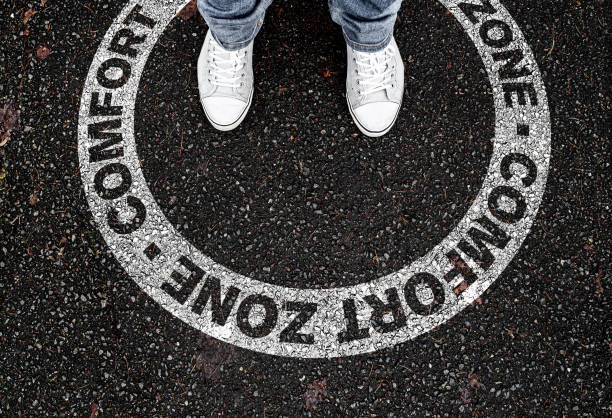 legs of person standing in circular marking on road with text COMFORT ZONE stock photo