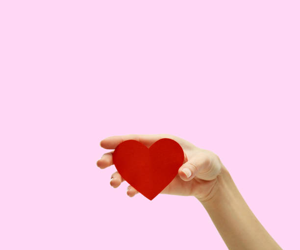 istock Hand holding small bright red heart on pink background, Valentine's day concept 1199470287