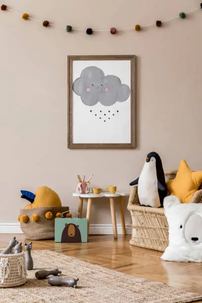 Stylish and modern scandinavian newborn baby interior with mock up photo or poster frame. Wooden toys and accessories.