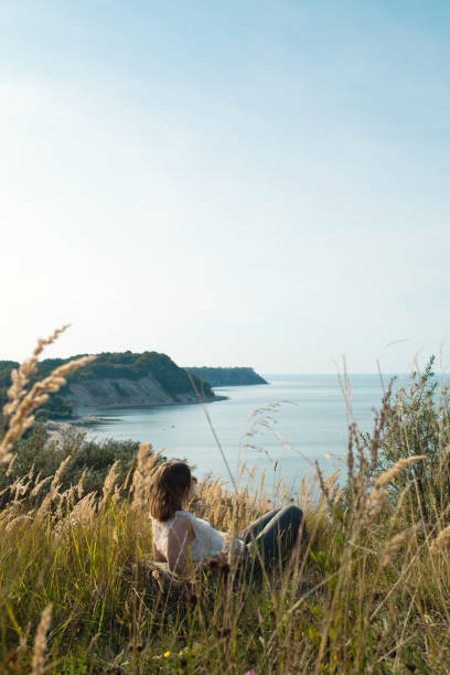 młoda dziewczyna ciesząc się naturą - mountain looking at view beach cliff zdjęcia i obrazy z banku zdjęć