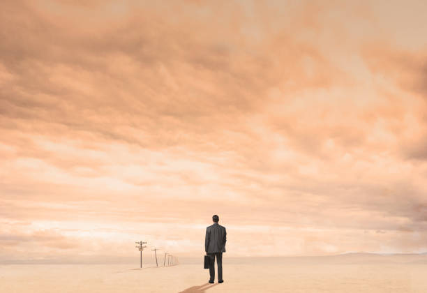 istock Businessman Standing On Dusty Plain Lined With Telephone Poles 1199478533