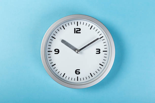 istock minimalistic white wall clock with light metal on a blue background. time concept. 1199479875