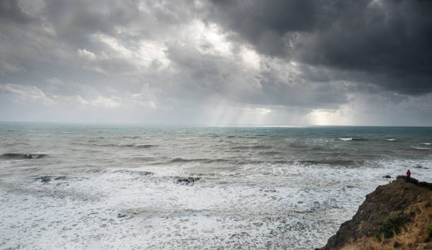 ドラマチックな嵐の海と空を楽しむ崖の端に立っている認識されていない人。 - cyprus paphos storm sea ストックフォトと画像