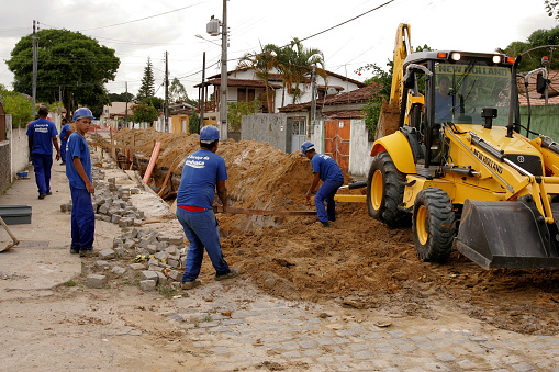 eunapolis, bahia / brazil - november 17, 2010: Workers and a backhoe excavate the street in the city of Eunapolis for implementation of the sewerage.