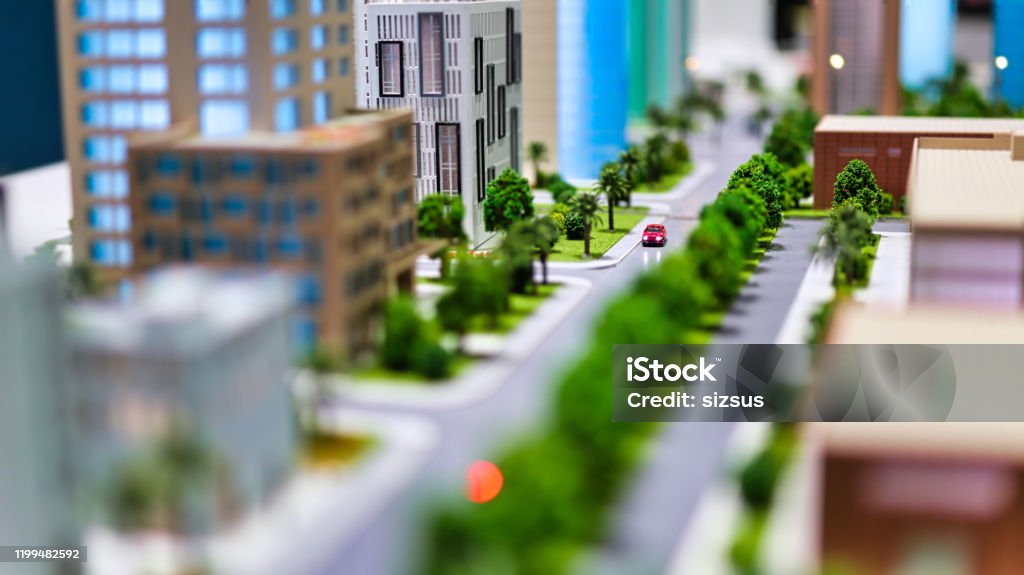 urban avenue modern generic contemporary style miniature model of glass buildings and streets with tilt-shift focus technique - focus is on the red car in the middle of the street City Stock Photo