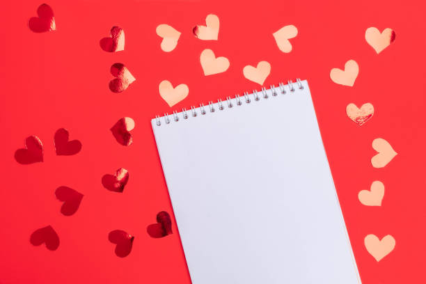 istock Valentine's Day background. Red hearts on red background with empty white notepad. Flat lay, top view with copy space 1199482839
