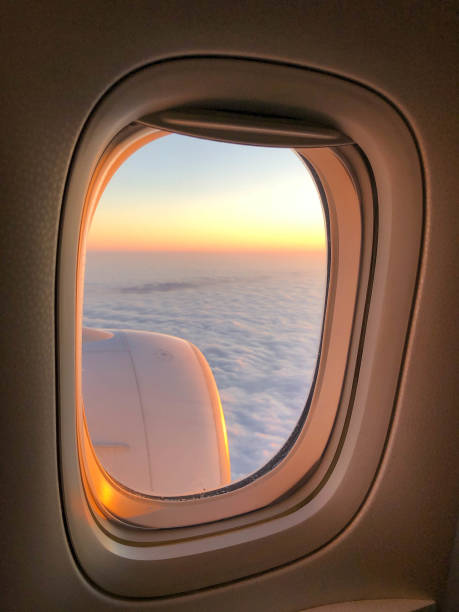 View through a commercial airplane window of the jet engine and a sunset sky