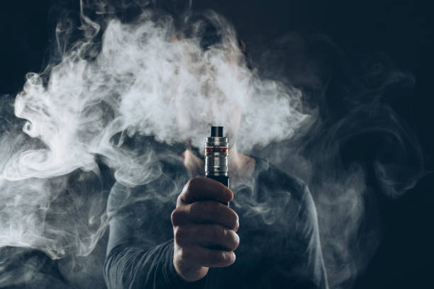 Vaping e-liquid from an electronic cigarette Vaping flavored e-liquid from an electronic cigarette thc photos stock pictures, royalty-free photos & images
