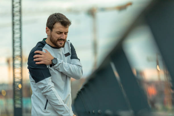 il bel giovane sportivo ha un infortunio fisico alla spalla durante un allenamento - spalla giuntura foto e immagini stock