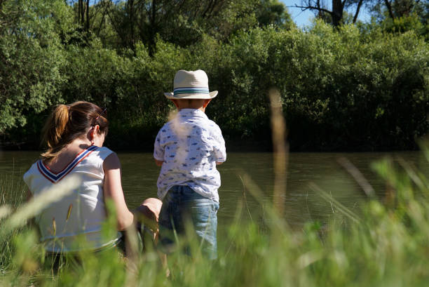 istock mother and son relaxing on green grass by the river 1199488428