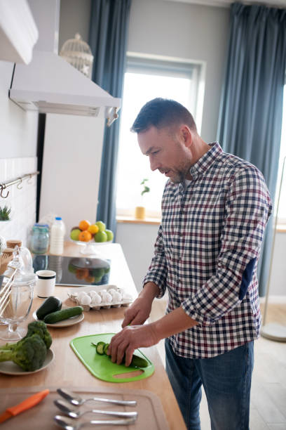 istock Man in a checkered shirt cutting vegetables 1199495391