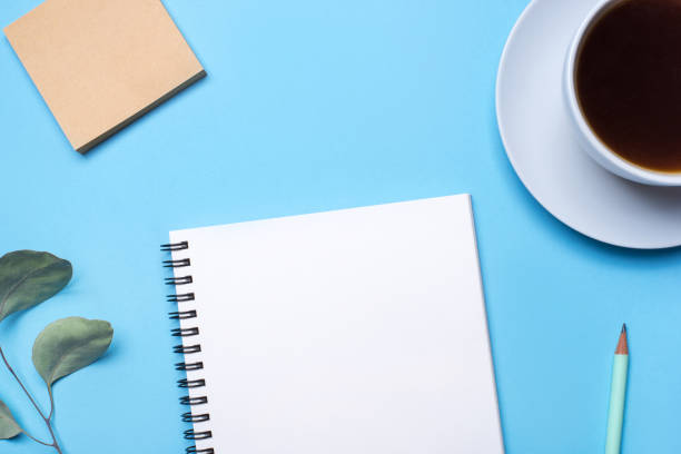 istock Blue background with notepad, pencil and cup of coffee. 1199497632