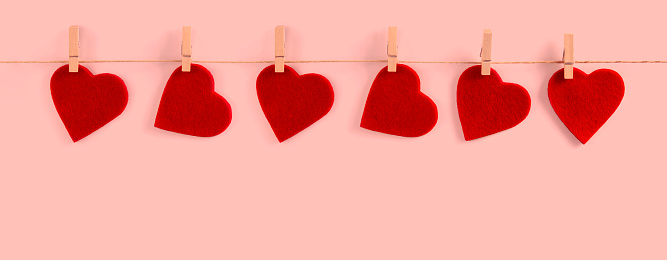 Valentine background with red felt hearts row border on clothespins on white background