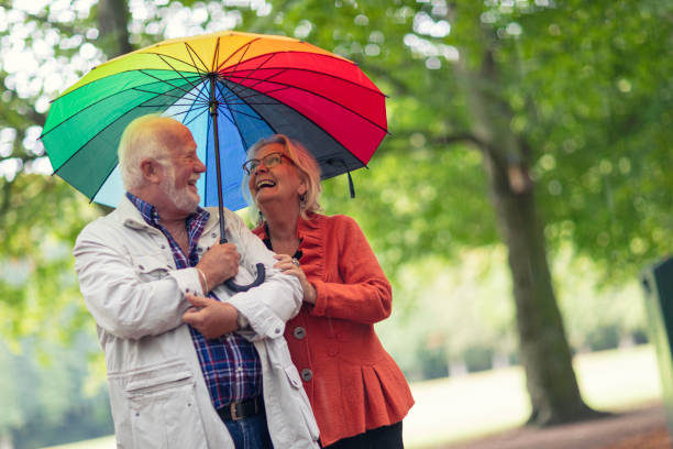 happy despite a sudden rain shower - umbrella senior adult couple autumn imagens e fotografias de stock