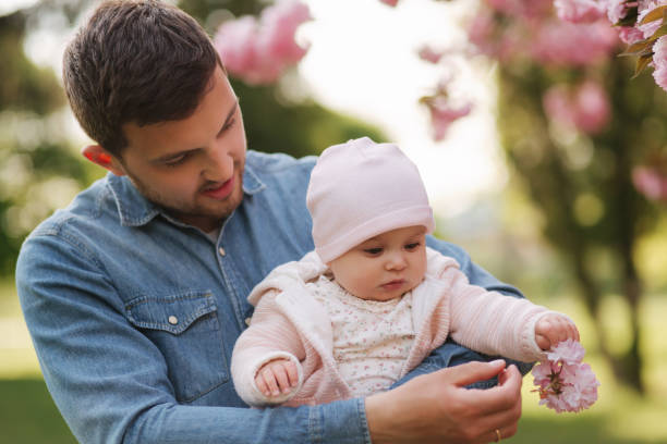 istock Dad with little daughter stand by the pink tree. Sakura 1199515076