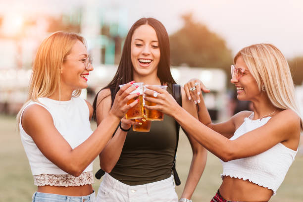 fermez-vous vers le haut des filles encourageant avec la bière au festival de musique - music festival park friendship summer photos et images de collection