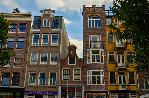 Amsterdam, Holland, August 2019. The typical and graceful houses: in the photo a lower one stands out among the other taller ones. Brightly colored brick facades.