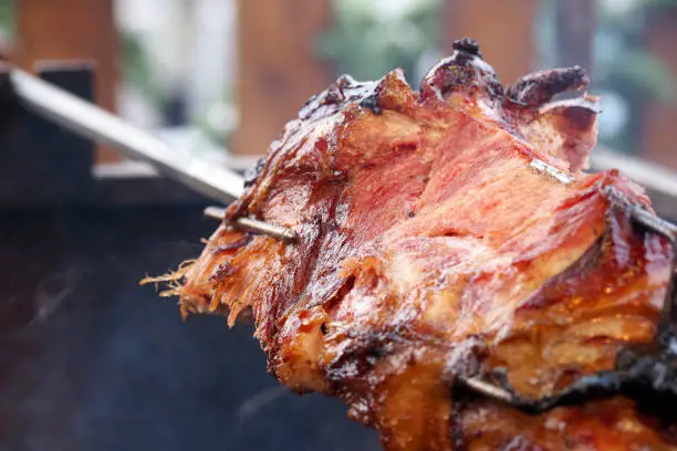 Photo of Barbecue leg of lamb on skewer, closeup. Barbecue grill in a street diner