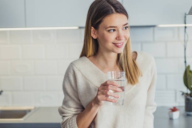 istock Young woman at home drinking water 1199520563