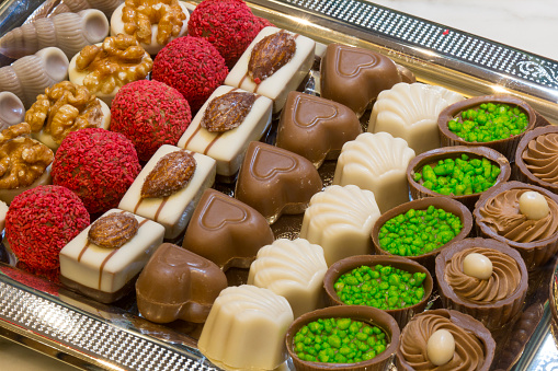 A combination of colorful and delicious chocolates on a silver platter. Sweets, patisserie, gift, happiness concepts. Horizontal close-up.