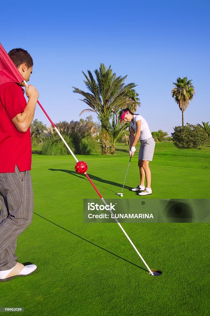 putting pelota de golf Mujer y hombre tiene una bandera - Foto de stock de Actividades recreativas libre de derechos