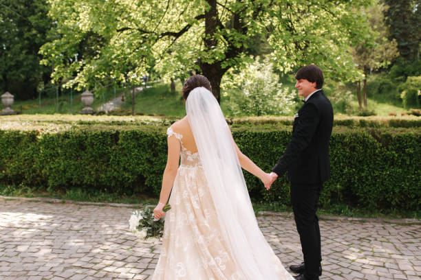 istock Groom and bride standing by the big tree in the park 1199532232