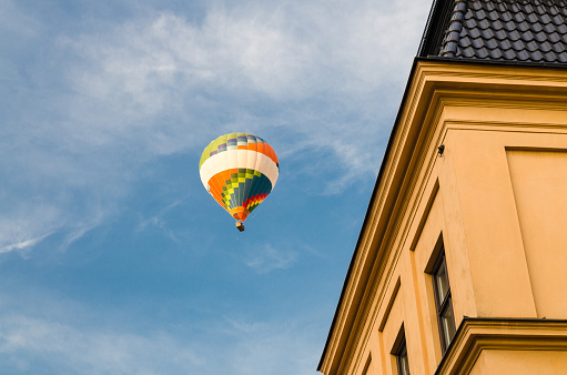 Colorful color hot air balloon in blue sky with white clouds over roofs of traditional typical yellow buildings in old historical town Gamla Stan with copy space, Stockholm, Sweden
