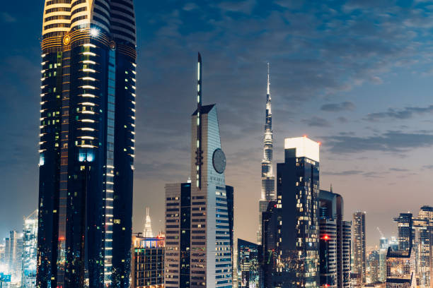 Downtown Dubai cityscape at sunset. Illuminated futuristic modern skyline and clear sky. Transitioning from day to night city lights begin to appear in the dark.